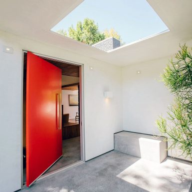 Ranch Redux - Exterior view of the front porch and red door. A large skylight and built-in bench complement the space. Photograph by Tomoko Matsubayashi.