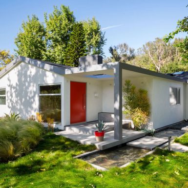 Ranch Redux - Exterior view of the home's red front door, with water feature and landscape in the foreground. Photograph by Trevor Tondro.