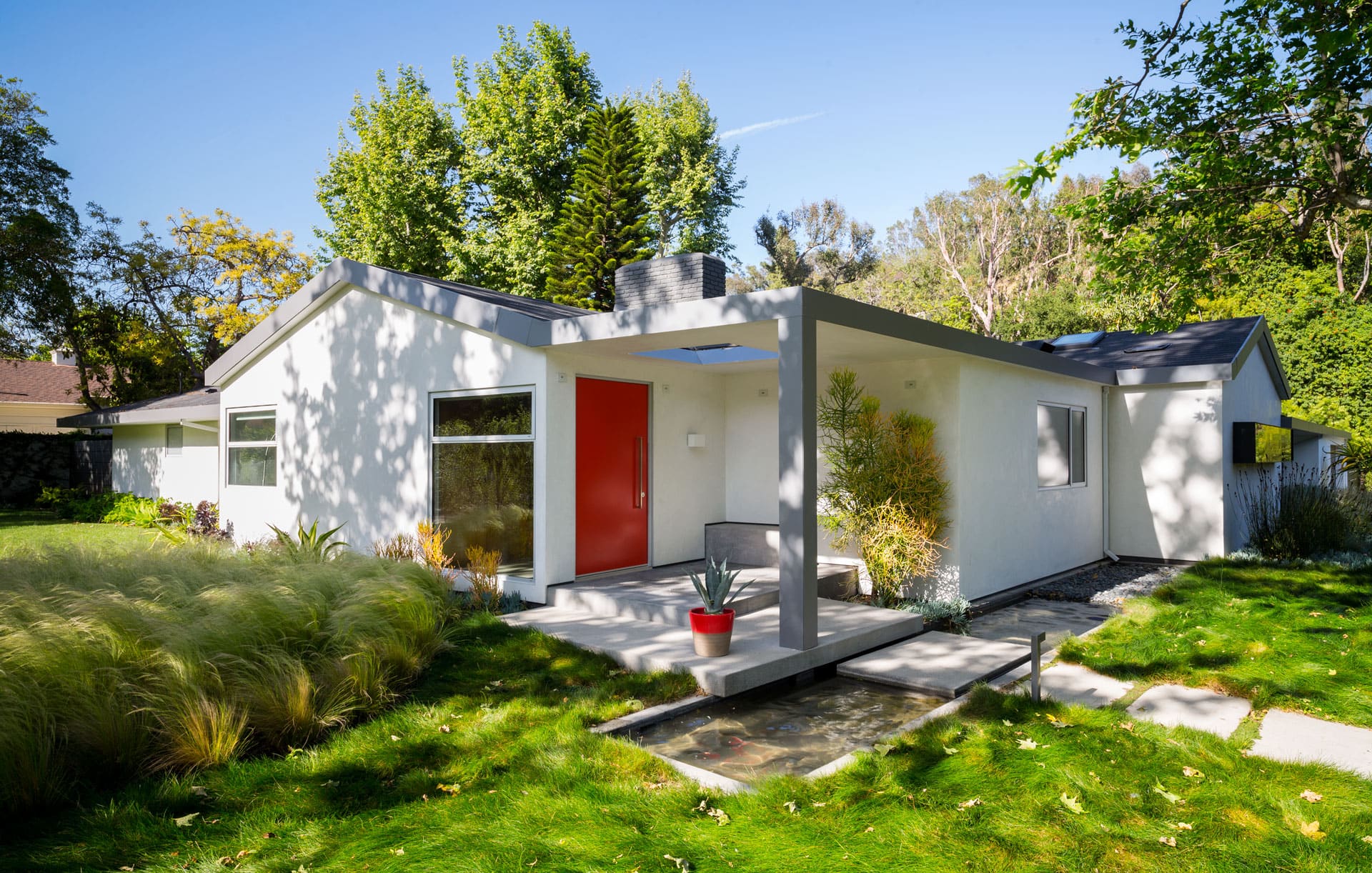 Ranch Redux - Exterior view of the home's red front door, with water feature and landscape in the foreground. Photograph by Trevor Tondro.