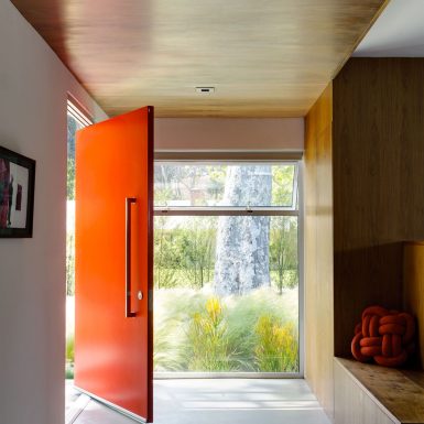 Ranch Redux - Interior view of entry and red front door, with wood ceiling and bench. Photograph by Trevor Tondro.