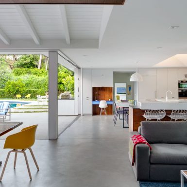 Ranch Redux - Interior view of light-filled modern den and kitchen, with pool visible through sliding doors. Photograph by Trevor Tondro.